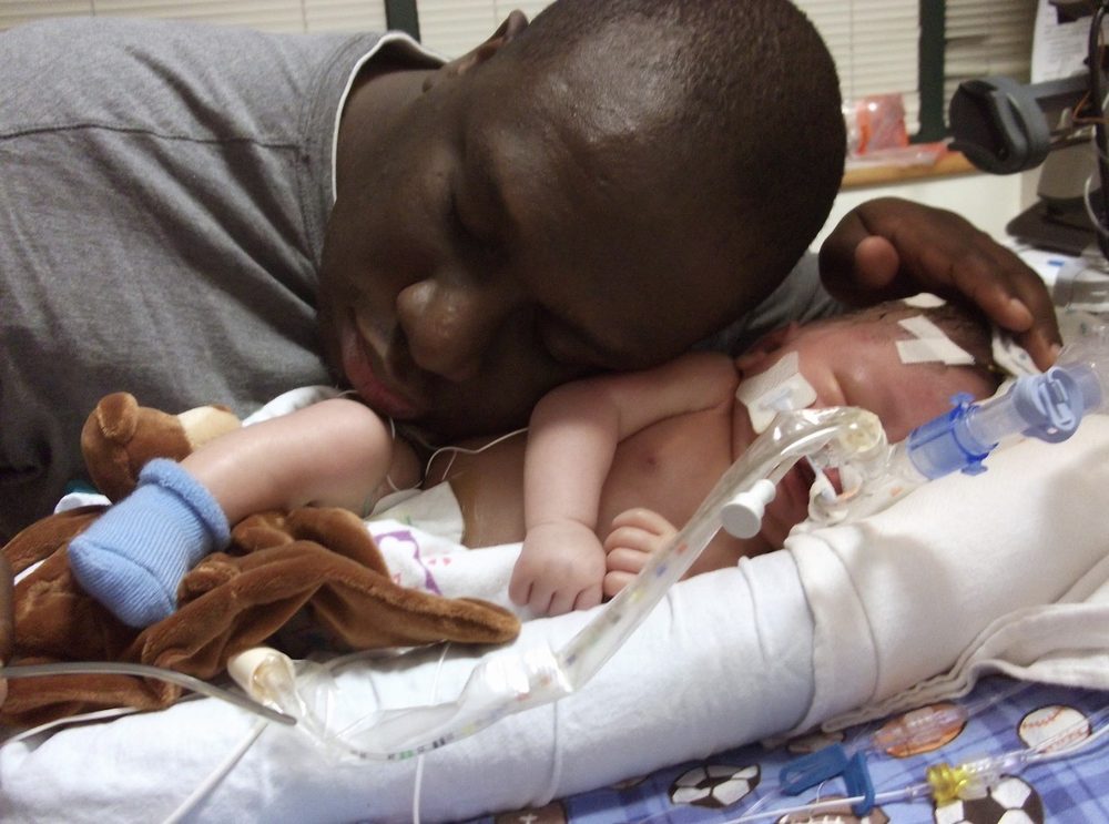 Anthony resting his head beside his son Drayden in the hospital, 2011